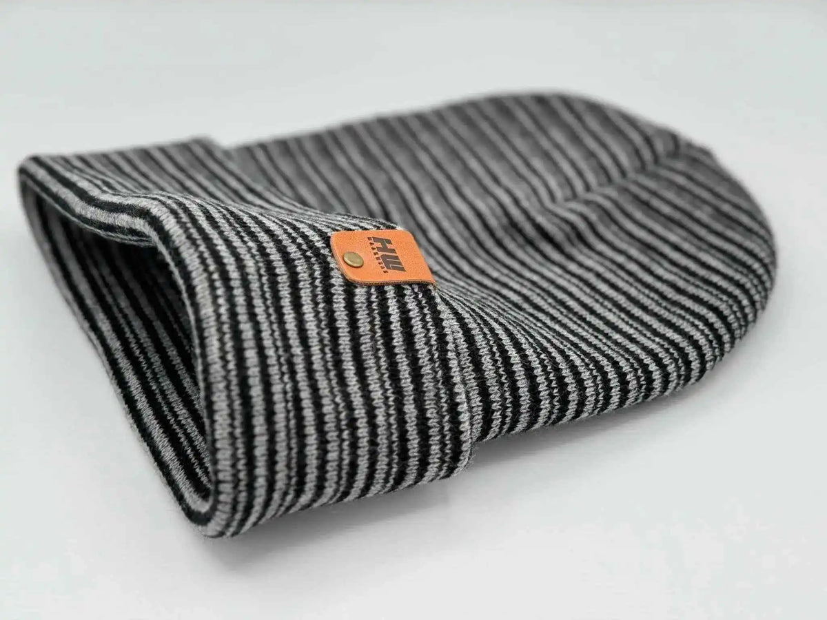Black-and-gray striped ribbed beanie with folded cuff, orange logo patch