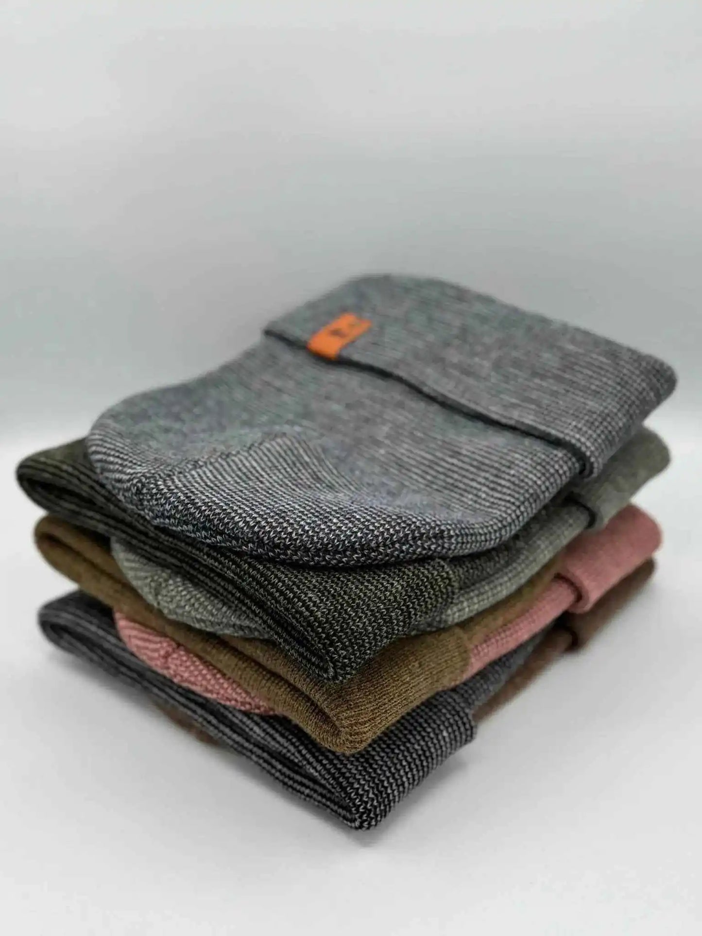 Stacked cuffed beanies in gray and darker tones with orange logo patch