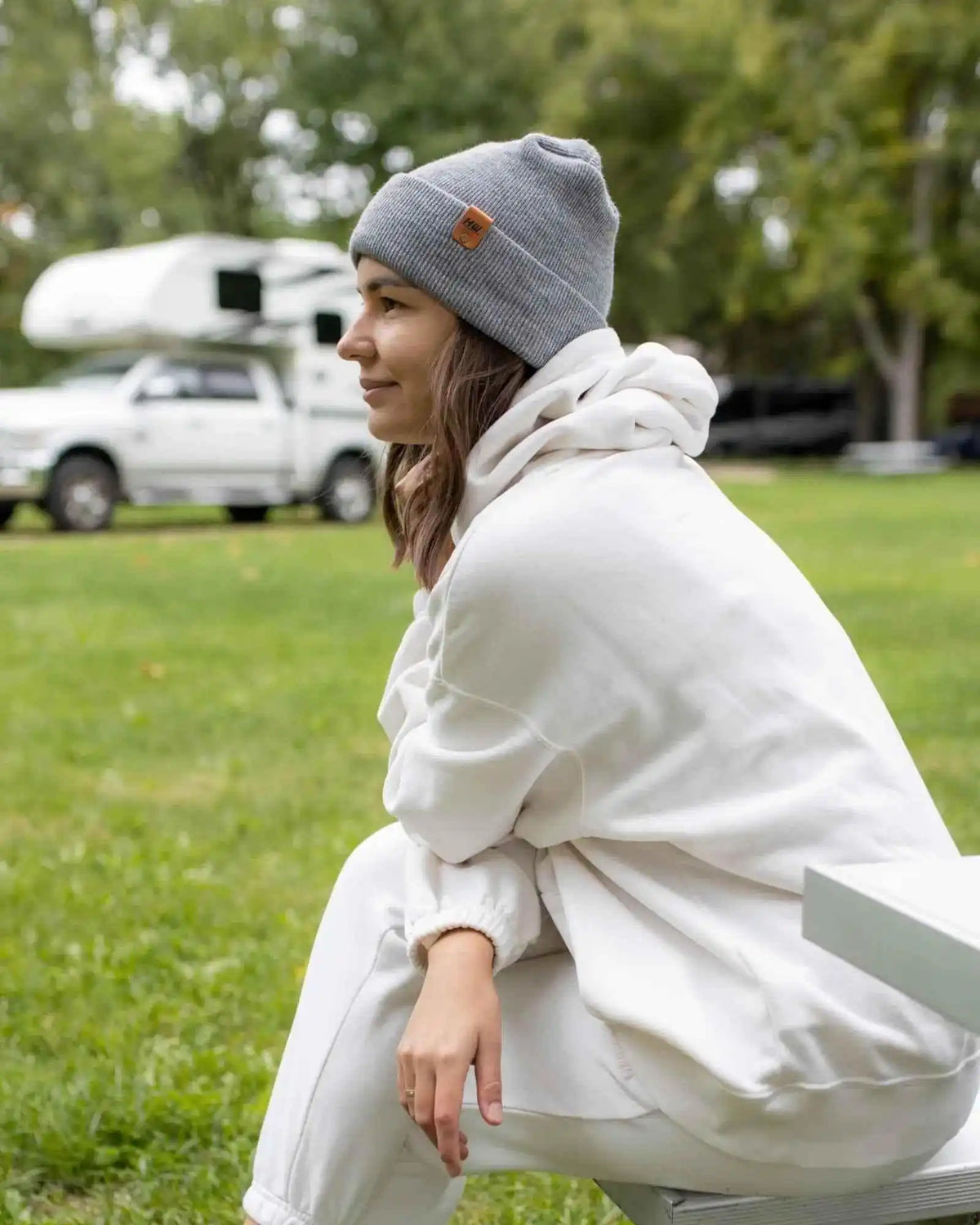 Gray cuffed knit beanie with small tan logo patch on folded brim