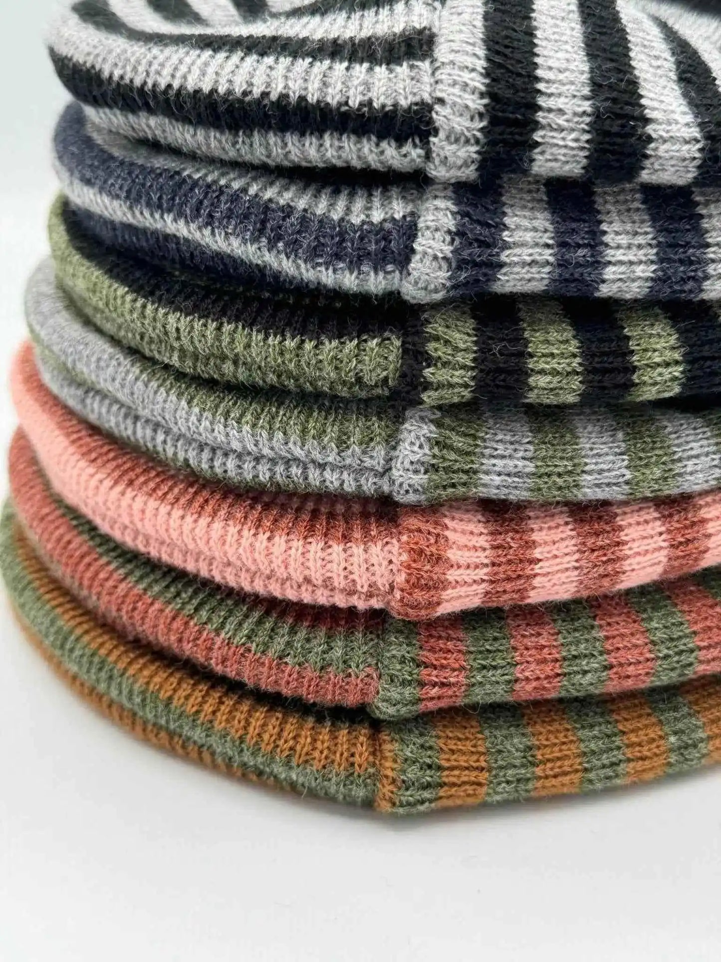 Stack of ribbed cuff knit beanies with multicolor striped pattern