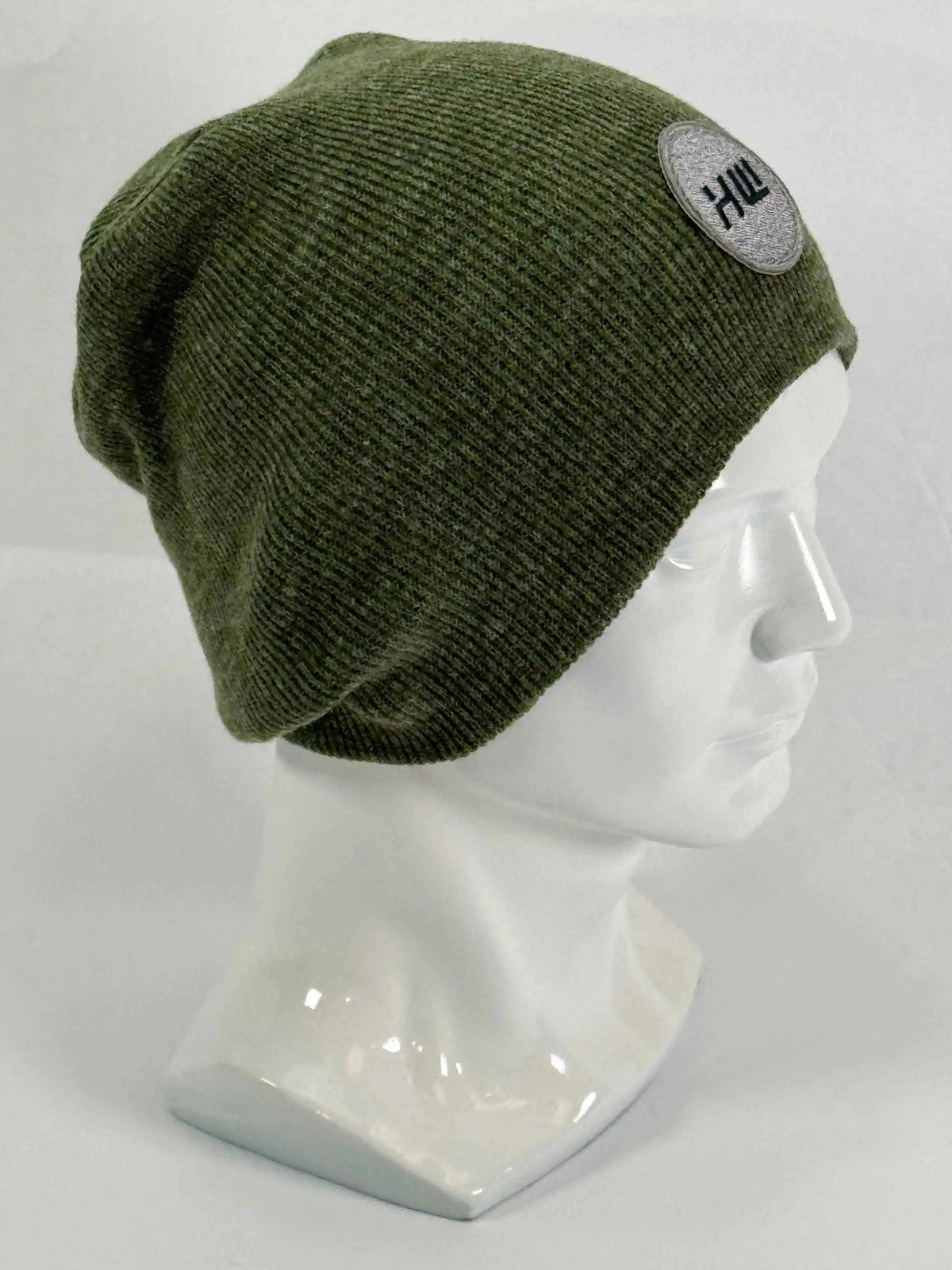Olive green knit beanie with un-cuffed rolled edge and round HUI logo patch.