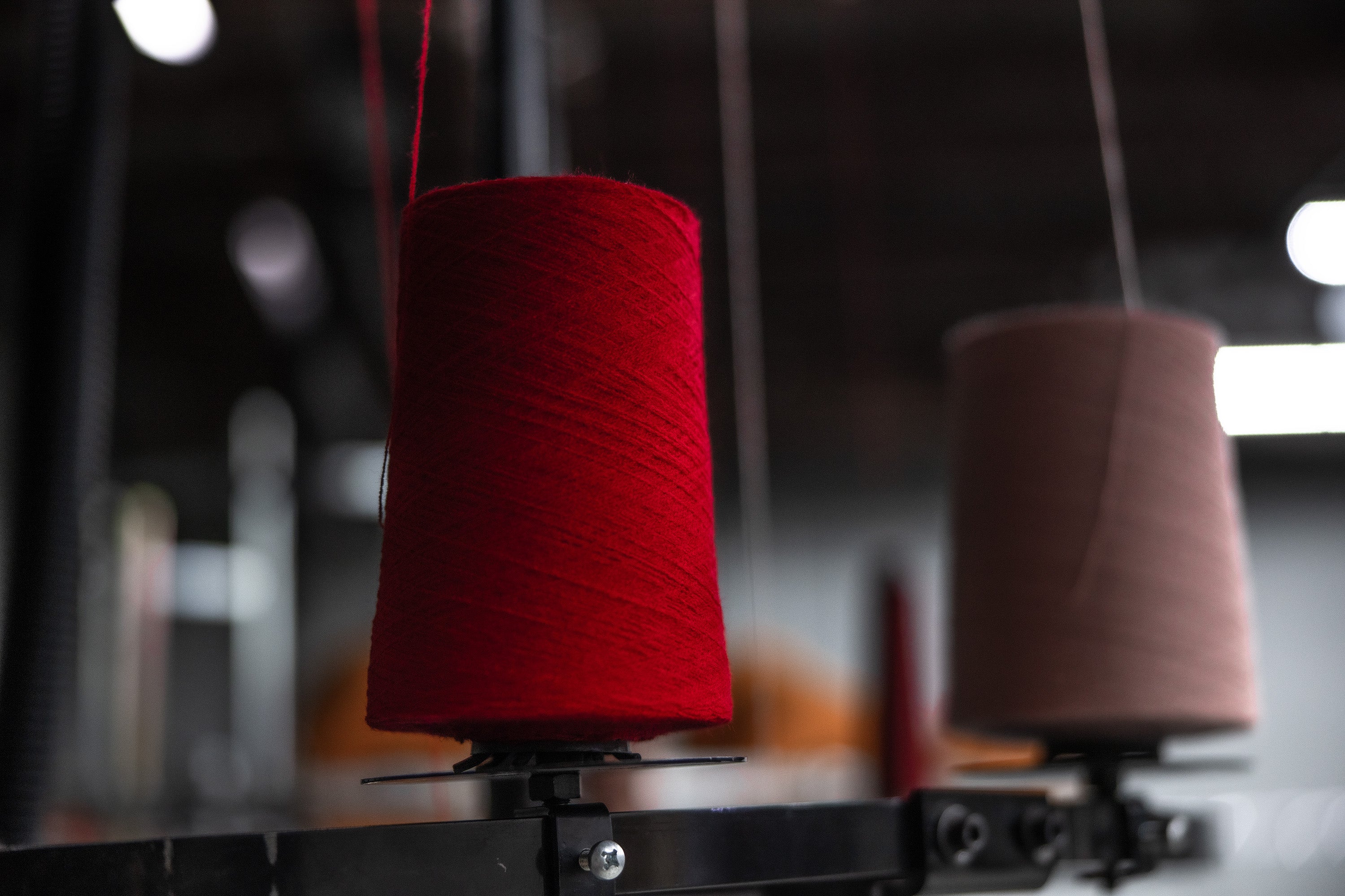 Red and brown spools of yarn on a machine with a blurred background