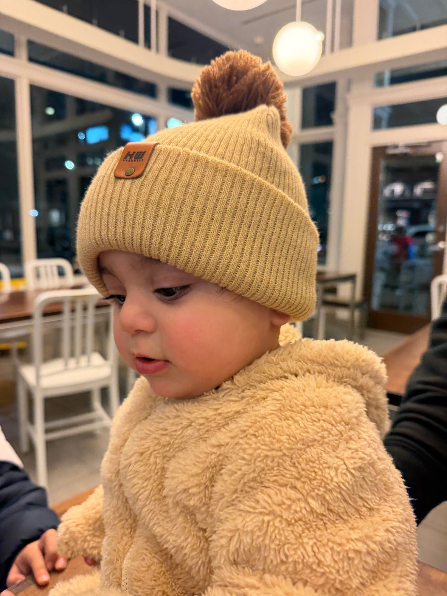 Baby wearing a beige winter hat from Haakwear made in USA collection for kids. 