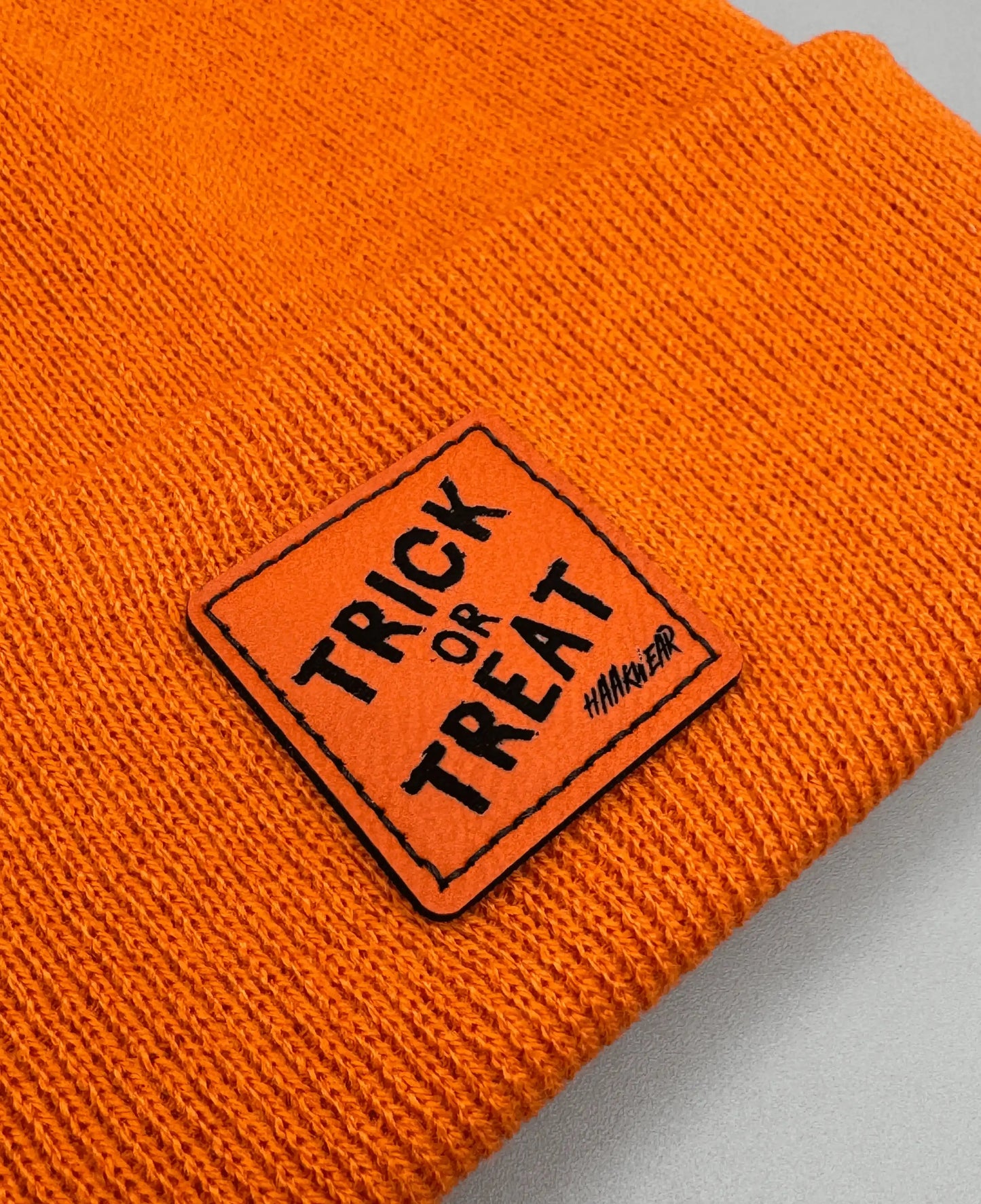 Orange knitted beanie with square “Trick or Treat” logo patch