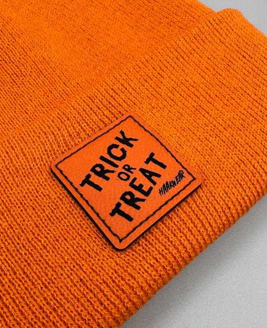 Orange knitted beanie with square “Trick or Treat” logo patch