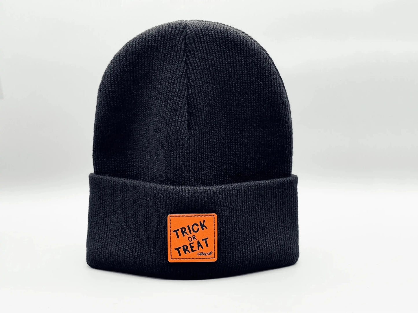 Dark blue beanie with orange “Trick or Treat” logo patch on cuff