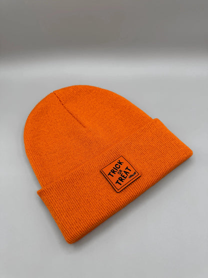 Orange beanie laid flat with square “Trick or Treat” logo patch