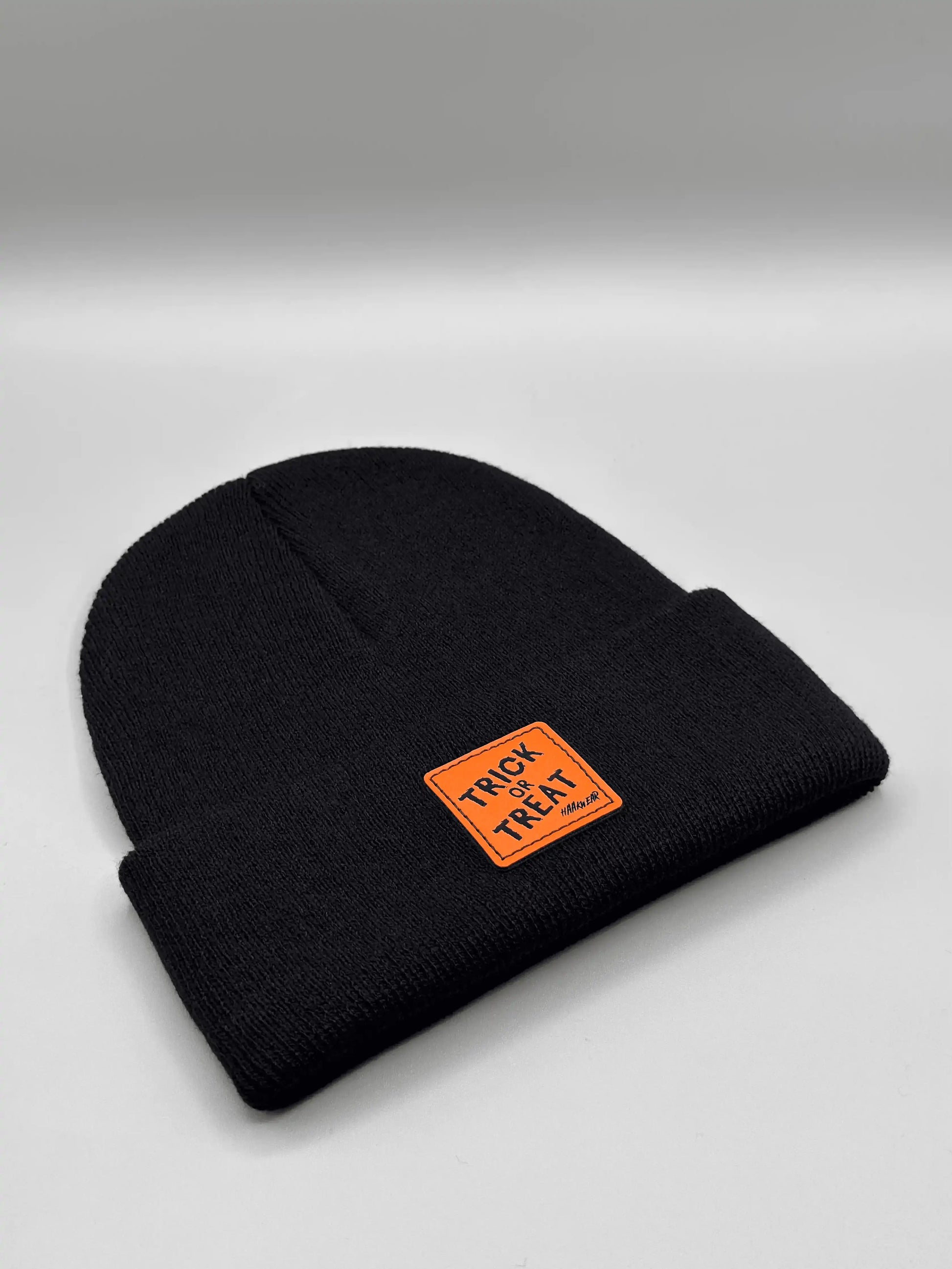 Dark beanie laid flat, orange “Trick or Treat” logo patch