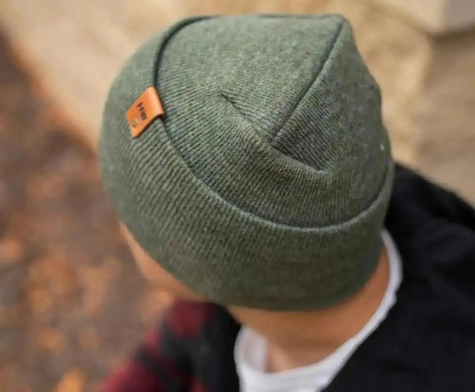 Forest green knit cuffed beanie with folded brim and small orange logo patch