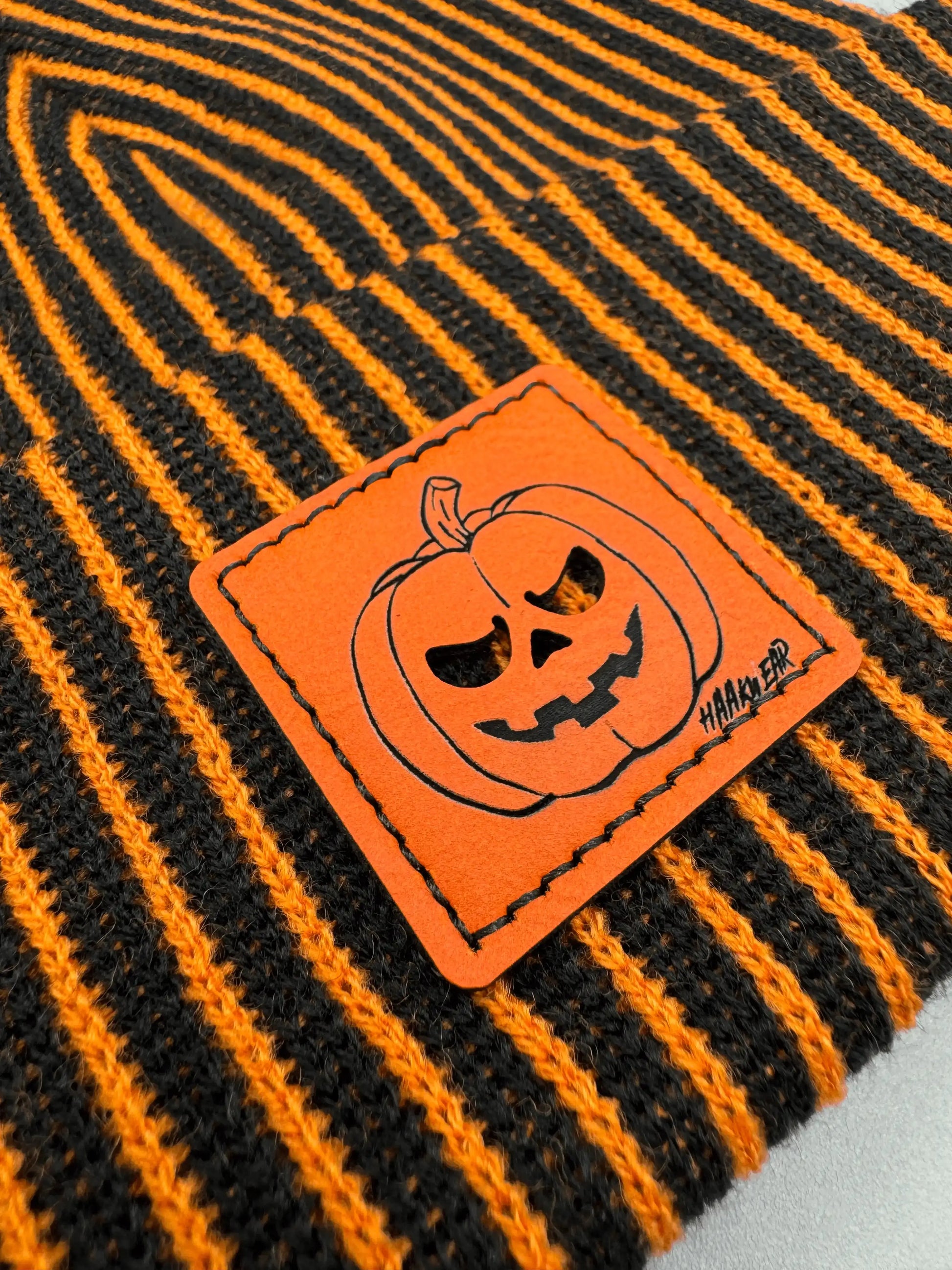 Striped knit beanie fabric with orange pumpkin face stitched patch