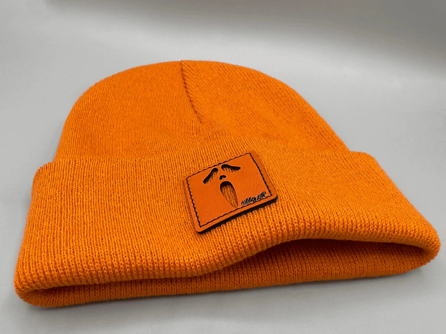 Orange knit beanie with folded brim and orange rectangular character patch