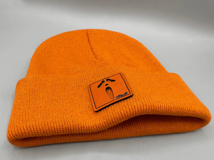 Orange knit beanie with folded brim and orange rectangular character patch