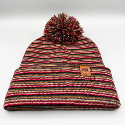 Multicolor striped knit beanie with large pom pom and tan logo patch, front view