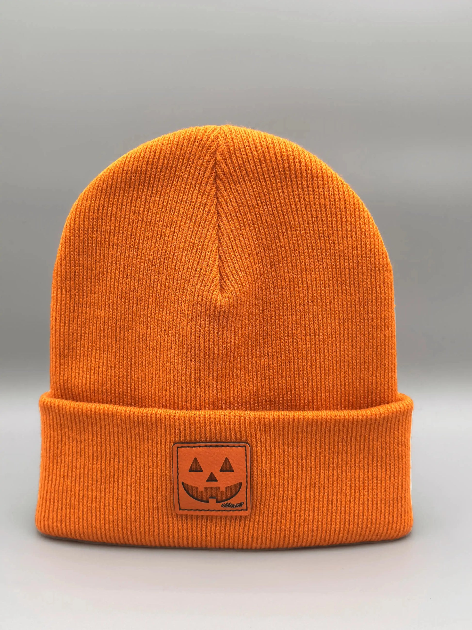 Orange beanie with fold-over cuff and jack-o-lantern emblem patch