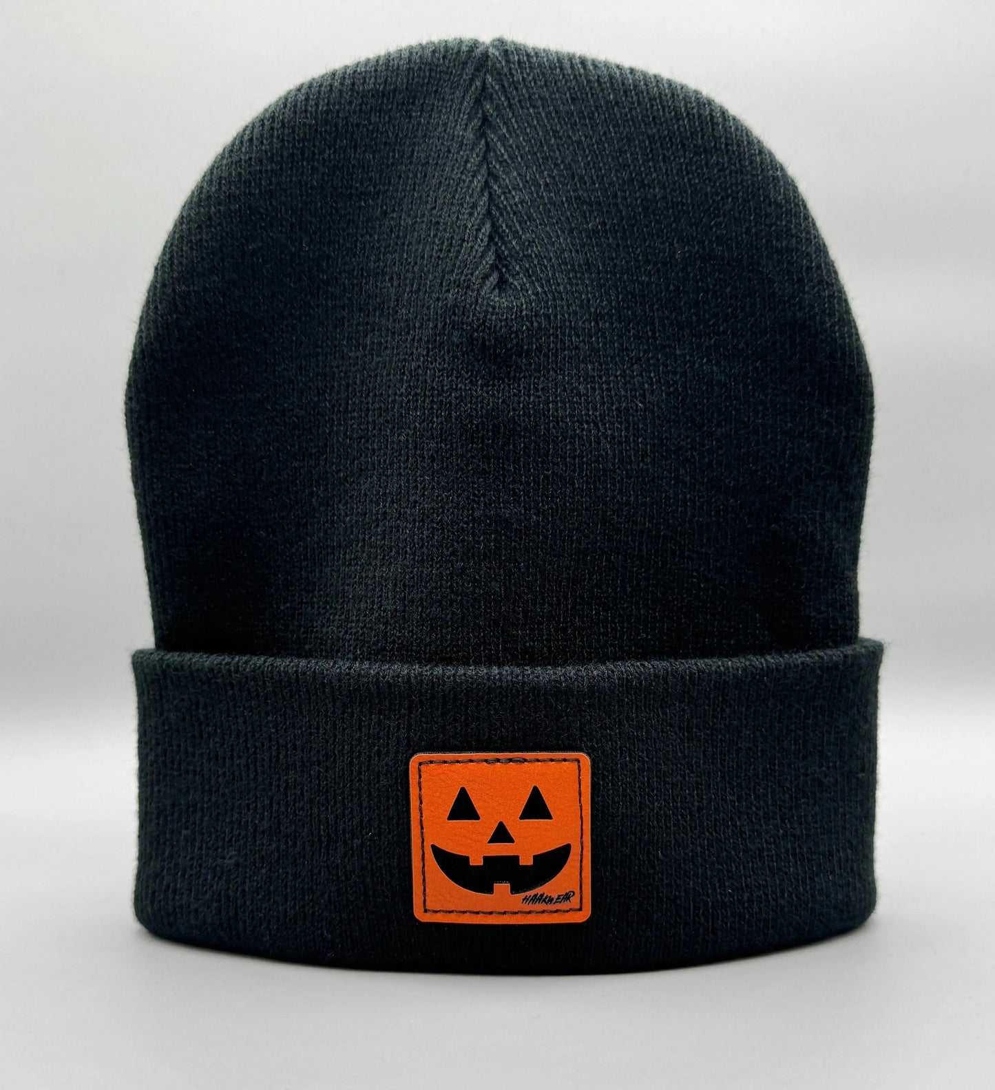 Black beanie with fold-over cuff and orange jack-o-lantern logo patch