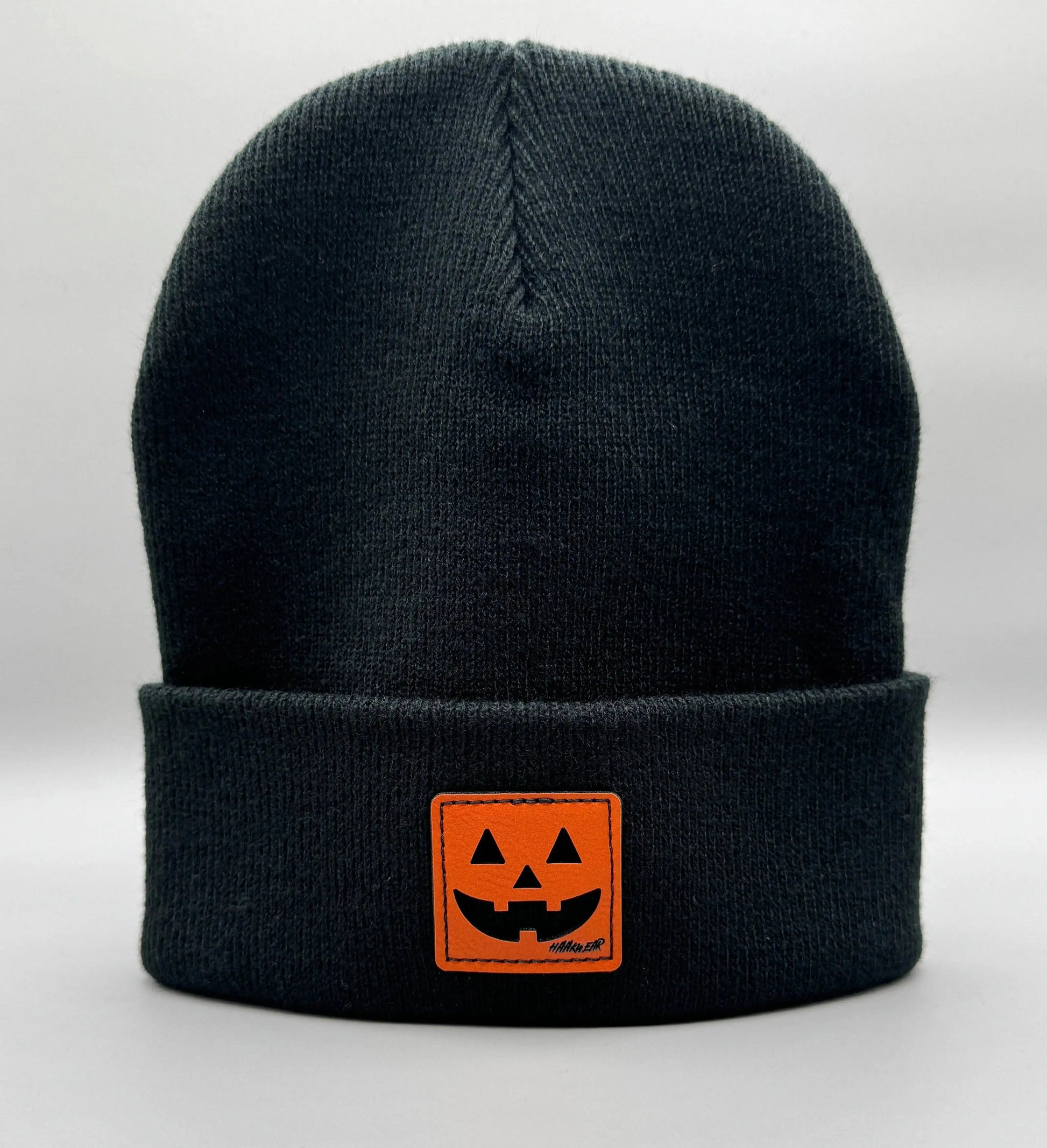Black beanie with fold-over cuff and orange jack-o-lantern logo patch