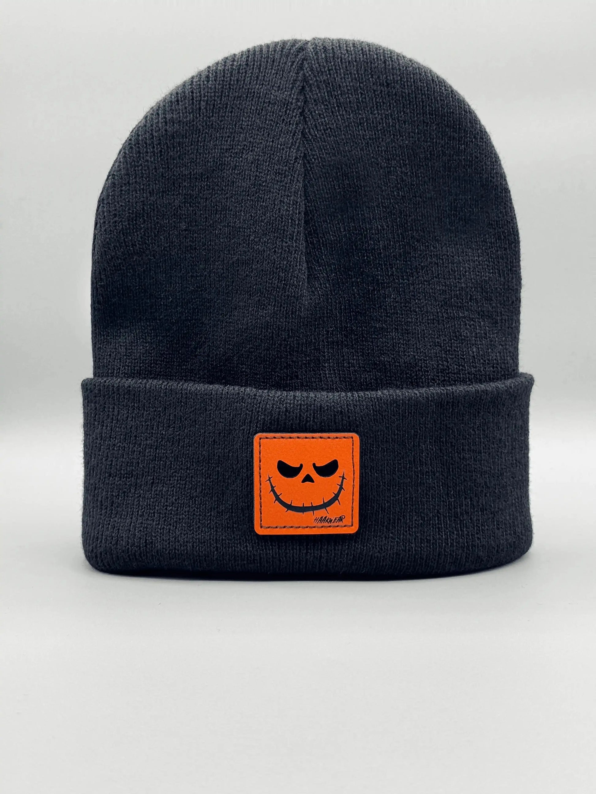 Dark blue knit beanie with orange jack-o-lantern patch on front