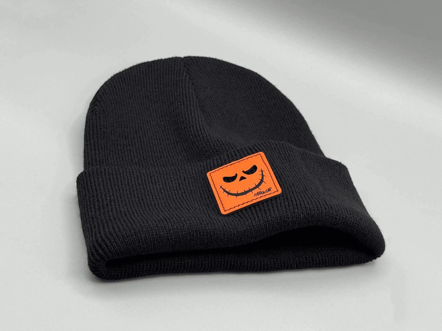 Black knit beanie with orange jack-o-lantern patch on front