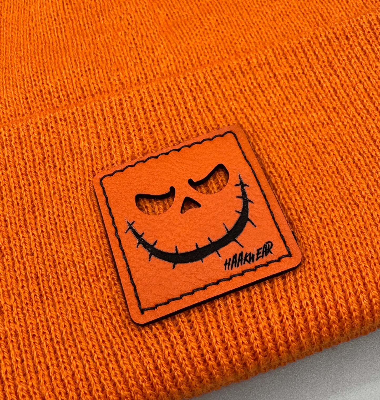 Orange jack-o-lantern face patch on orange knit beanie cuff
