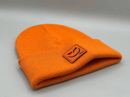 Orange knit beanie folded with small jack-o-lantern patch on front