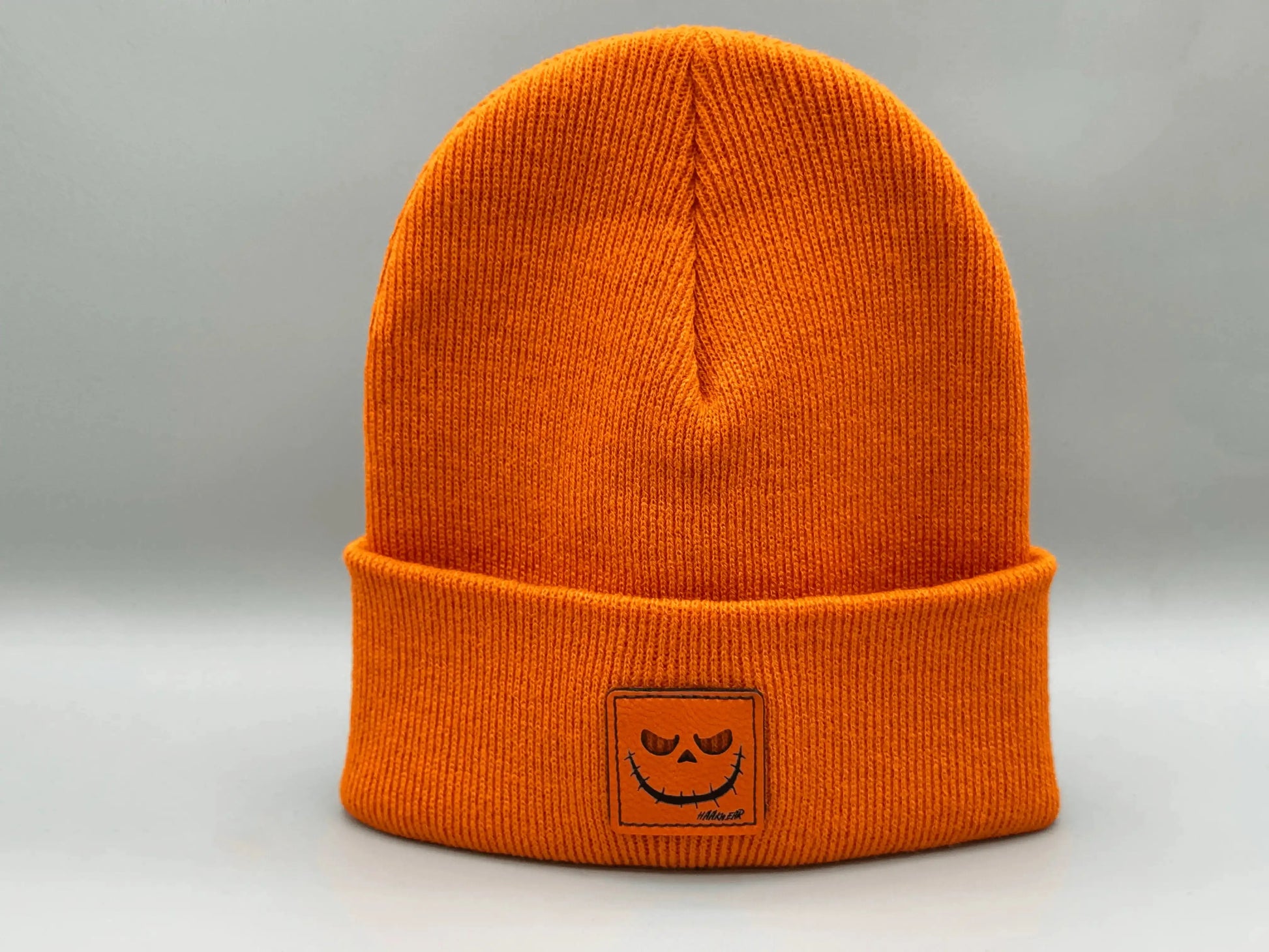Orange knit beanie with jack-o-lantern patch on cuff