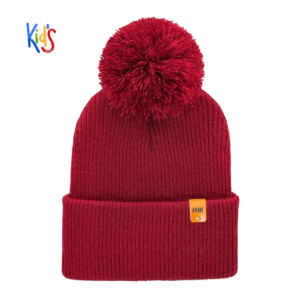 Burgundy red knit kids beanie with ribbed cuff, large pom pom, and small logo patch