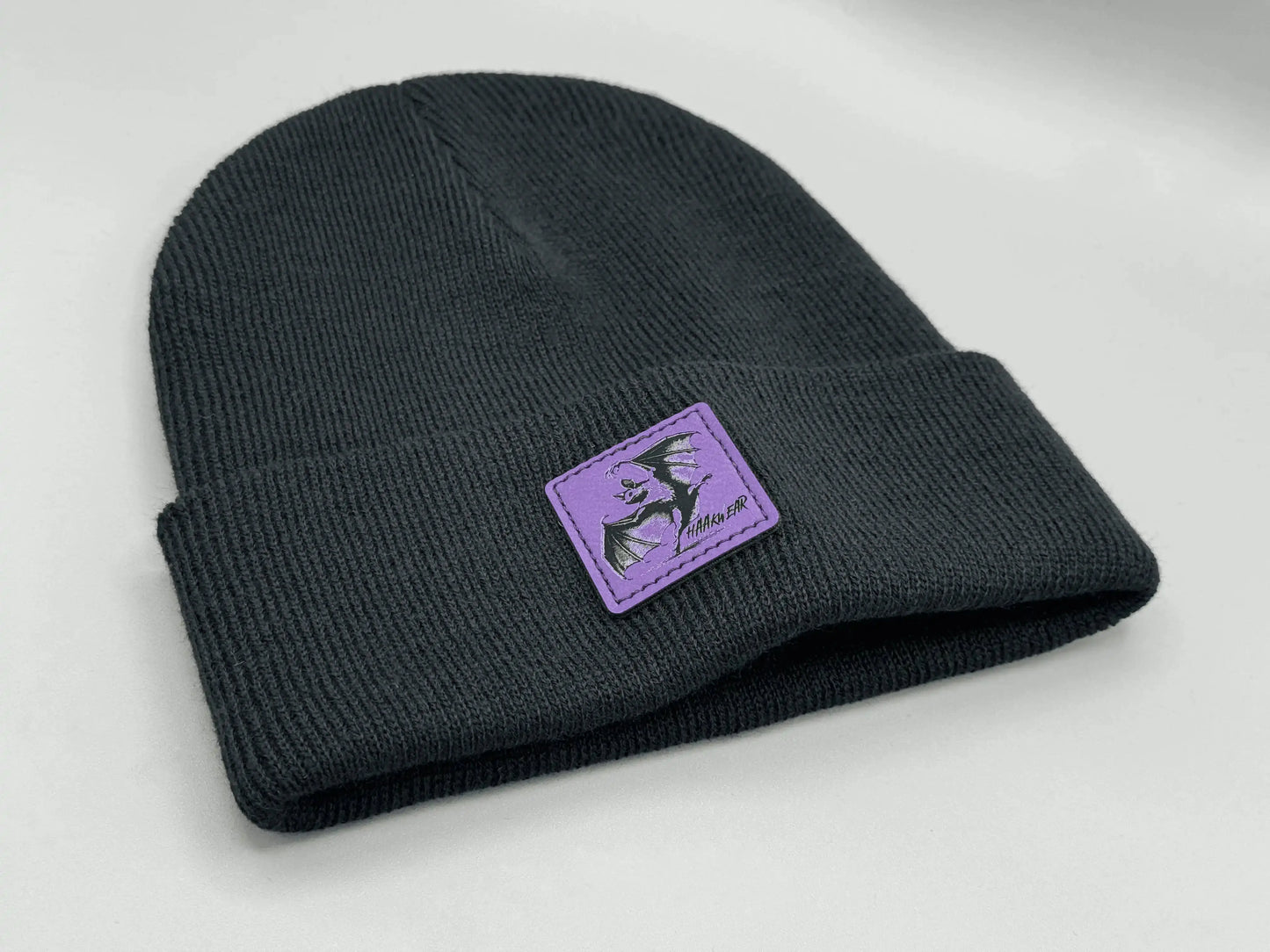 Dark navy knit beanie with purple square logo patch on the side