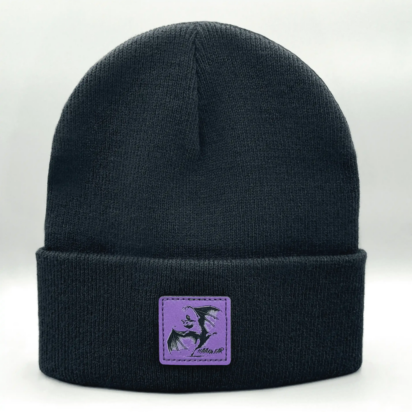 Dark navy knit beanie with purple square patch featuring a witch silhouette