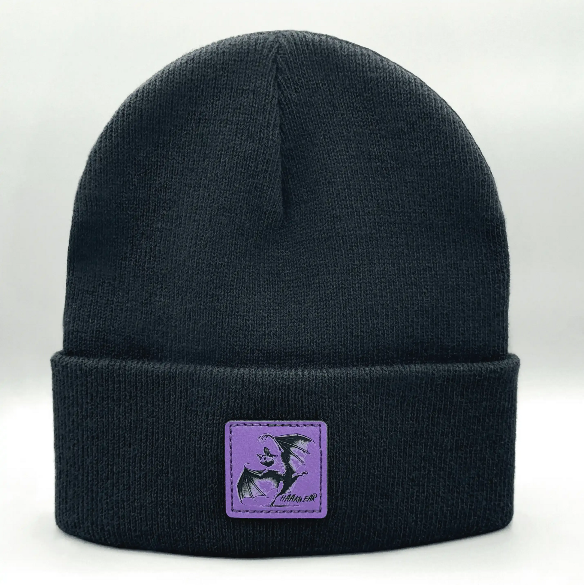 Dark navy knit beanie with purple square patch featuring a witch silhouette
