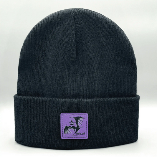 Dark navy knit beanie with purple square patch featuring a witch silhouette