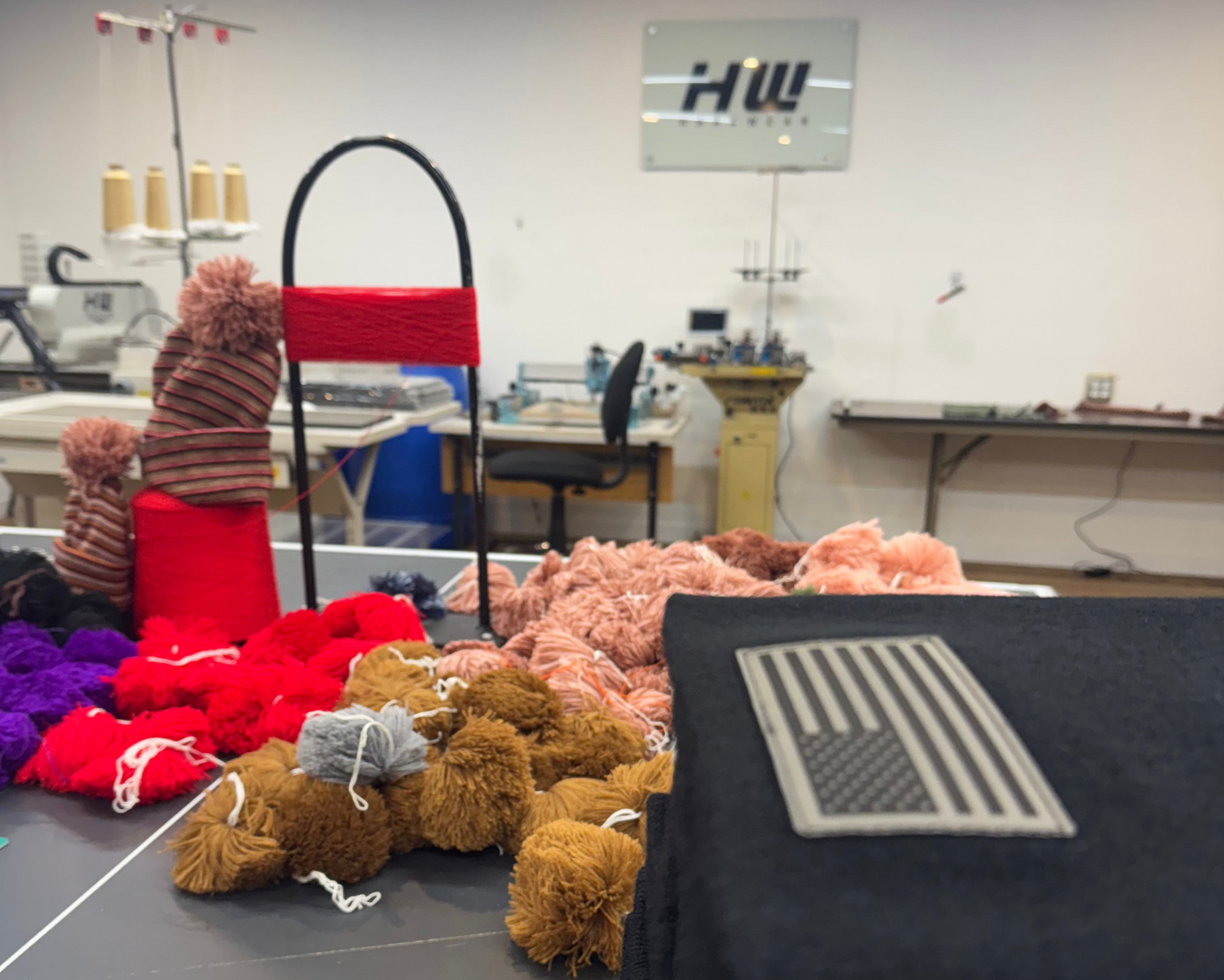 a picture of beanie with Pom Poms and the haakwear logo in the background. Customized beanies made by haakwear. 