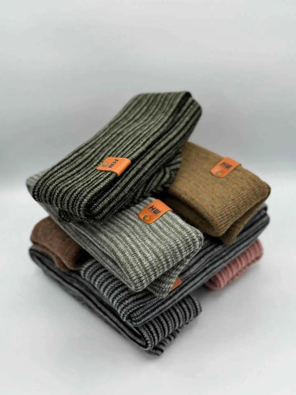 Stack of striped knit beanies with fold-over cuffs and orange logo patches