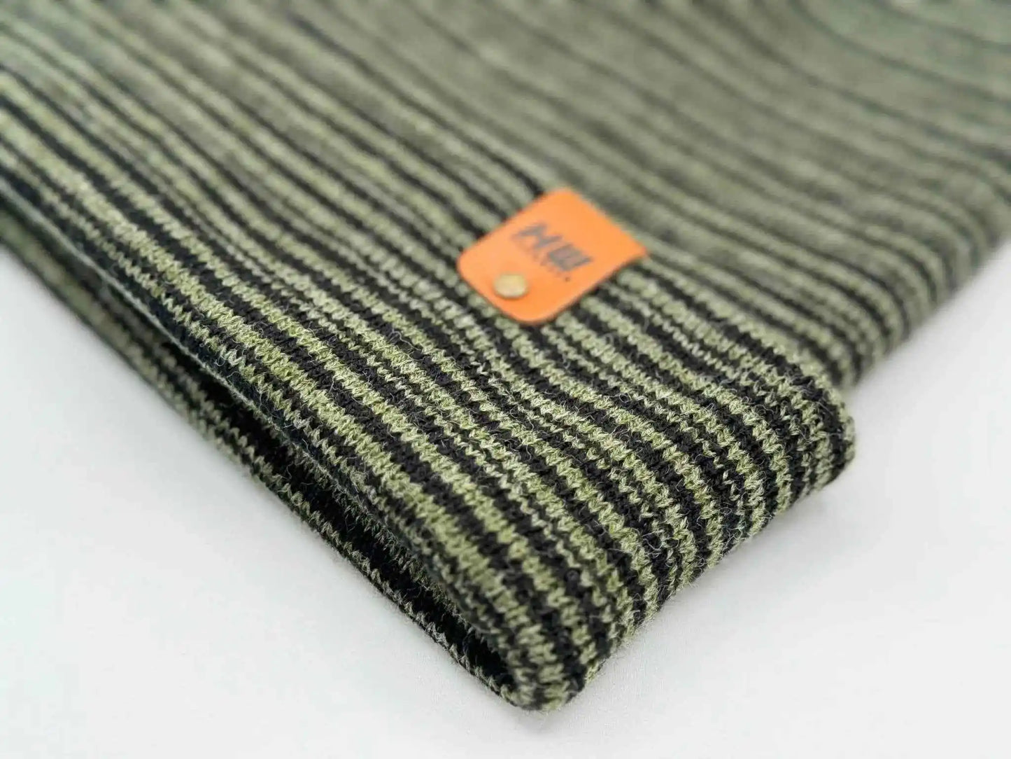 Knit beanie cuff corner with orange logo patch and dark green striped texture