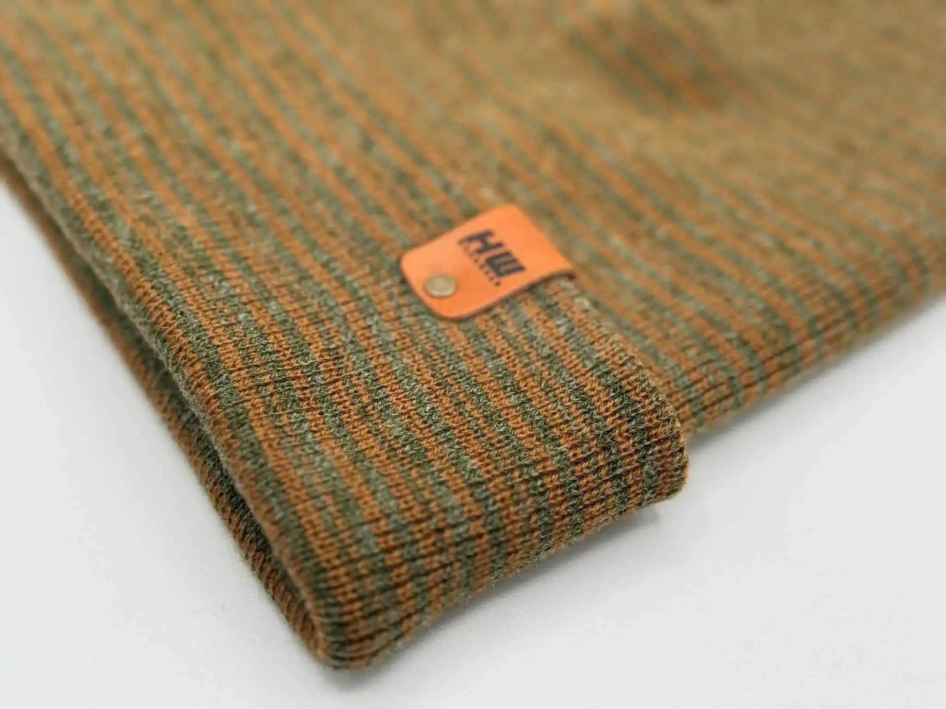 Brown and green contrast beanie with orange logo label on knit cuff