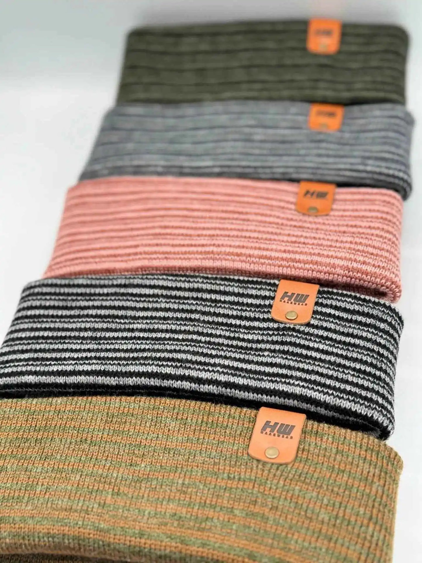 Ribbed cuff beanie stack in black, pink, orange, and green with orange logo patches