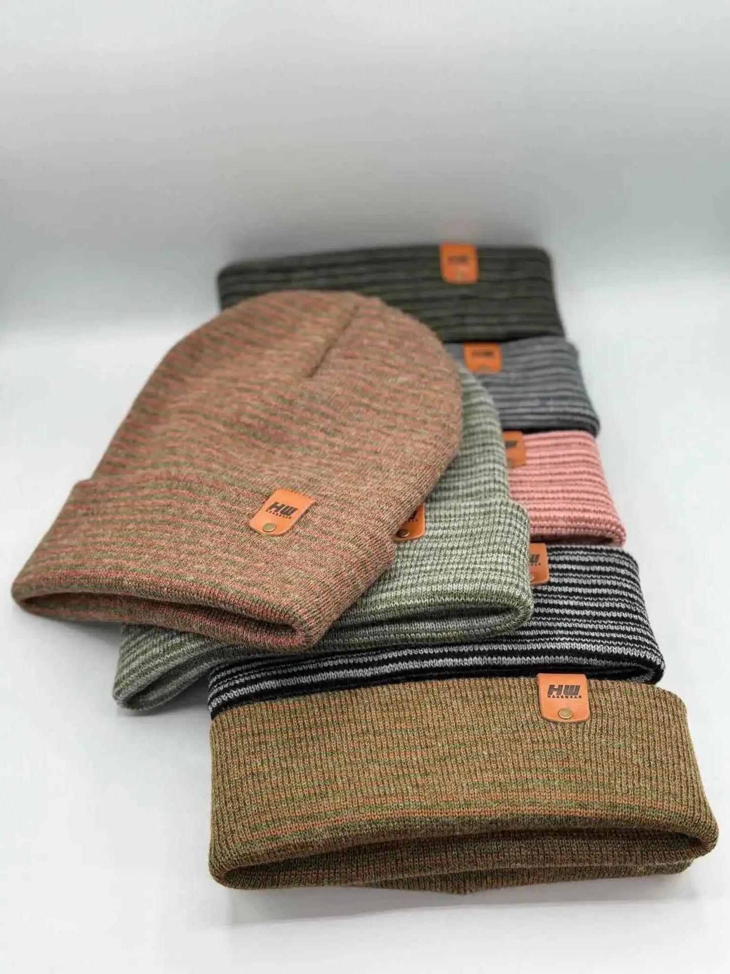 Stack of contrast cuff beanies in burgundy/green, gray, pink, and tan with orange labels