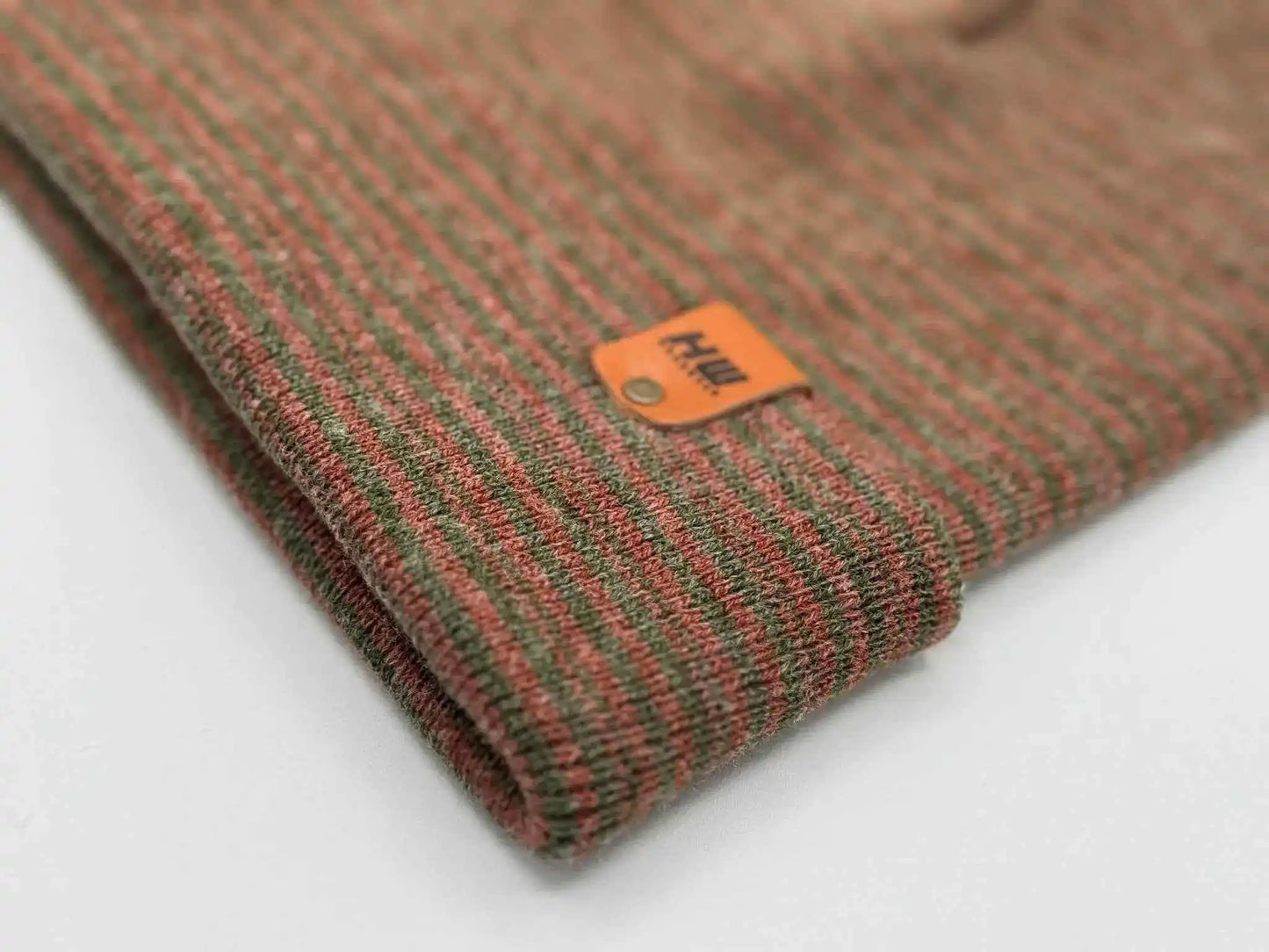 Burgundy/green contrast cuff beanie close-up with striped knit and orange logo patch