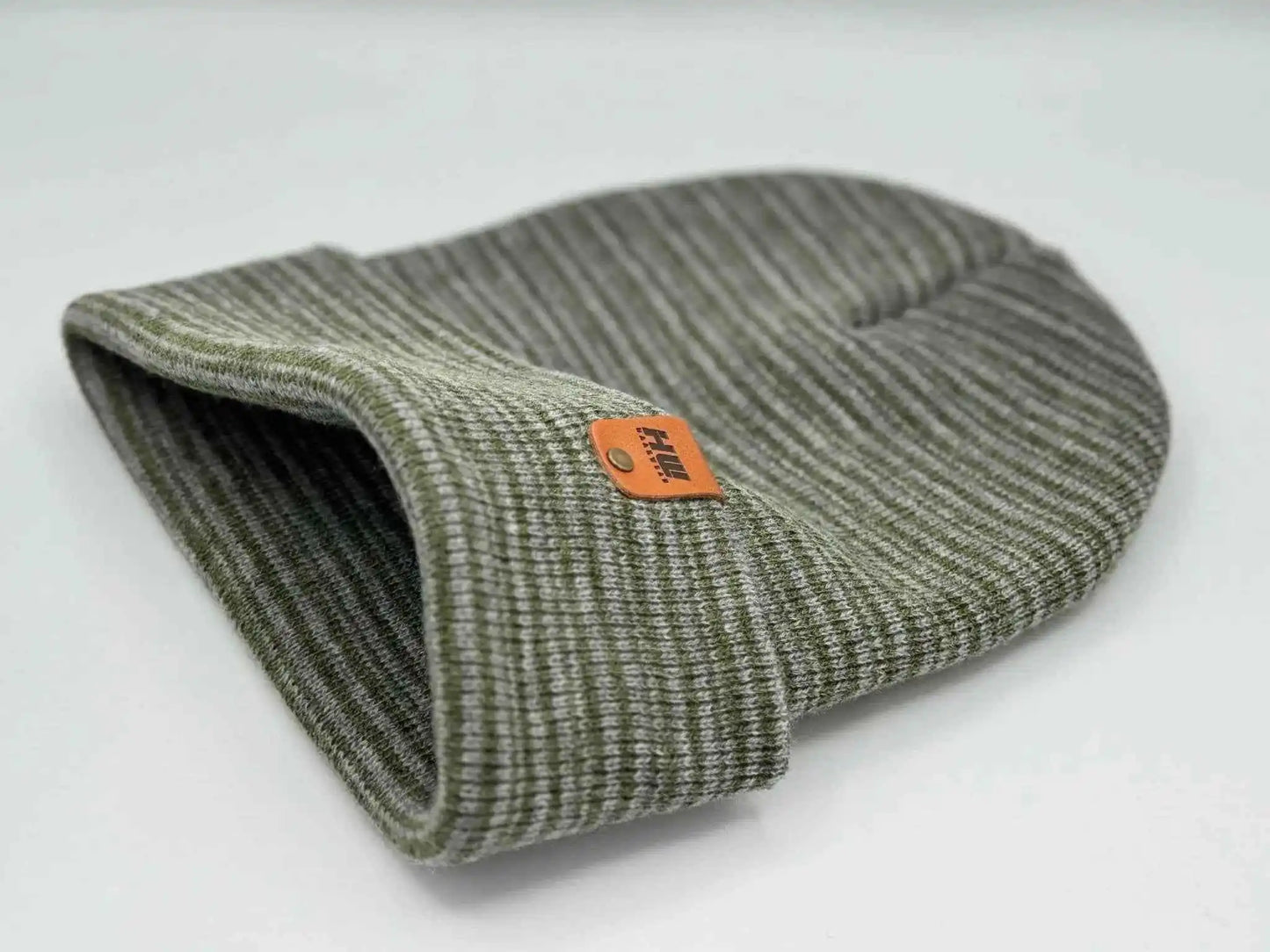 Gray-green knit beanie with folded cuff, side view, orange logo patch