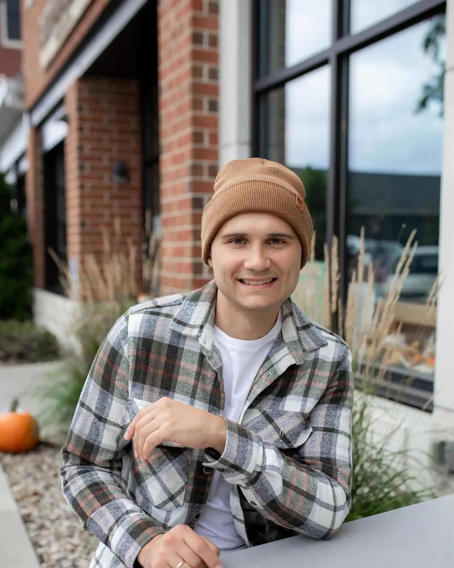 Camel brown knit beanie with folded cuff and logo patch, worn by man