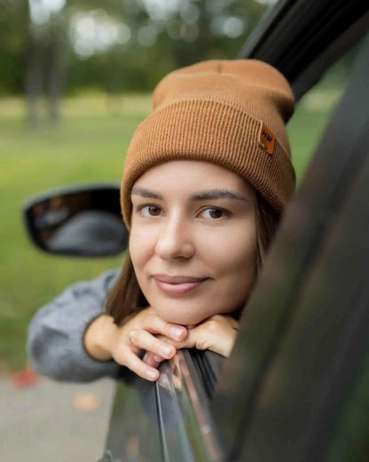 Camel brown cuffed knit beanie with side logo patch, worn by woman