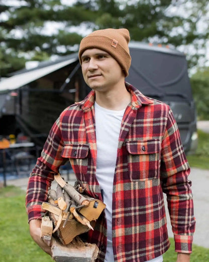 Camel brown beanie with folded cuff and logo patch, worn with plaid shirt