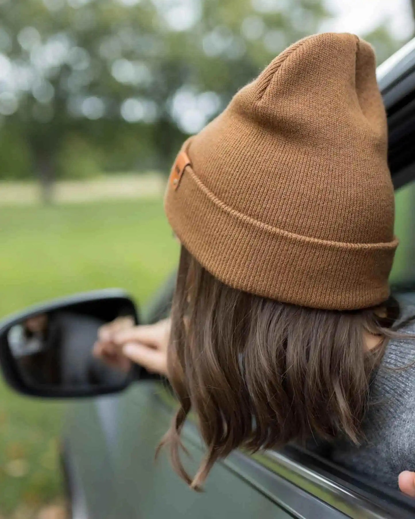 Camel brown knit beanie, folded cuff visible, small side logo patch