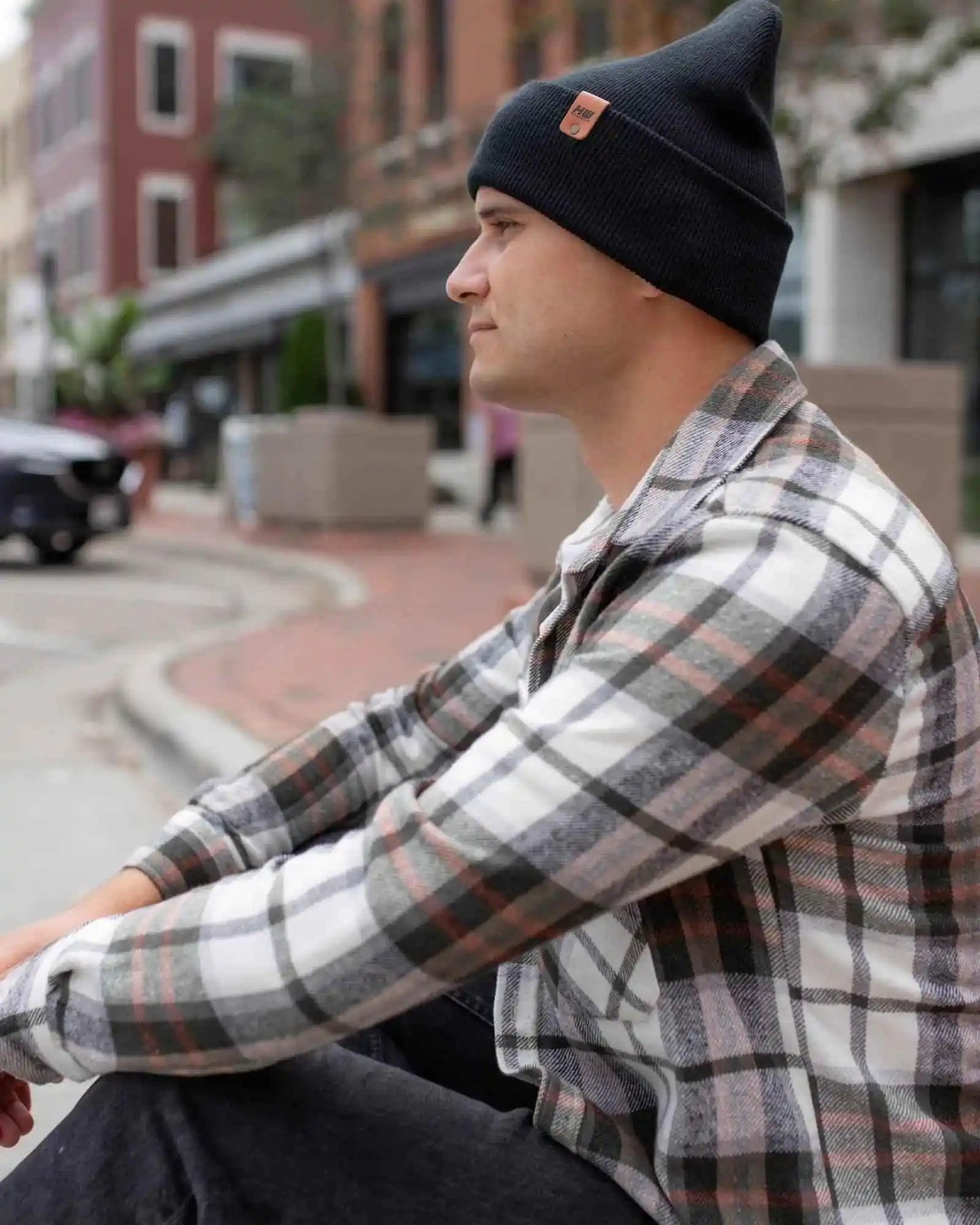Charcoal black cuffed beanie with fold-over brim and small logo patch on side.