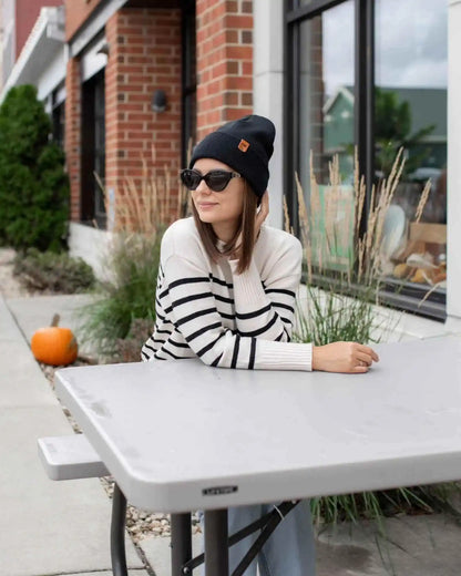 Charcoal black cuffed beanie with fold-over brim and small leather logo tag on side.