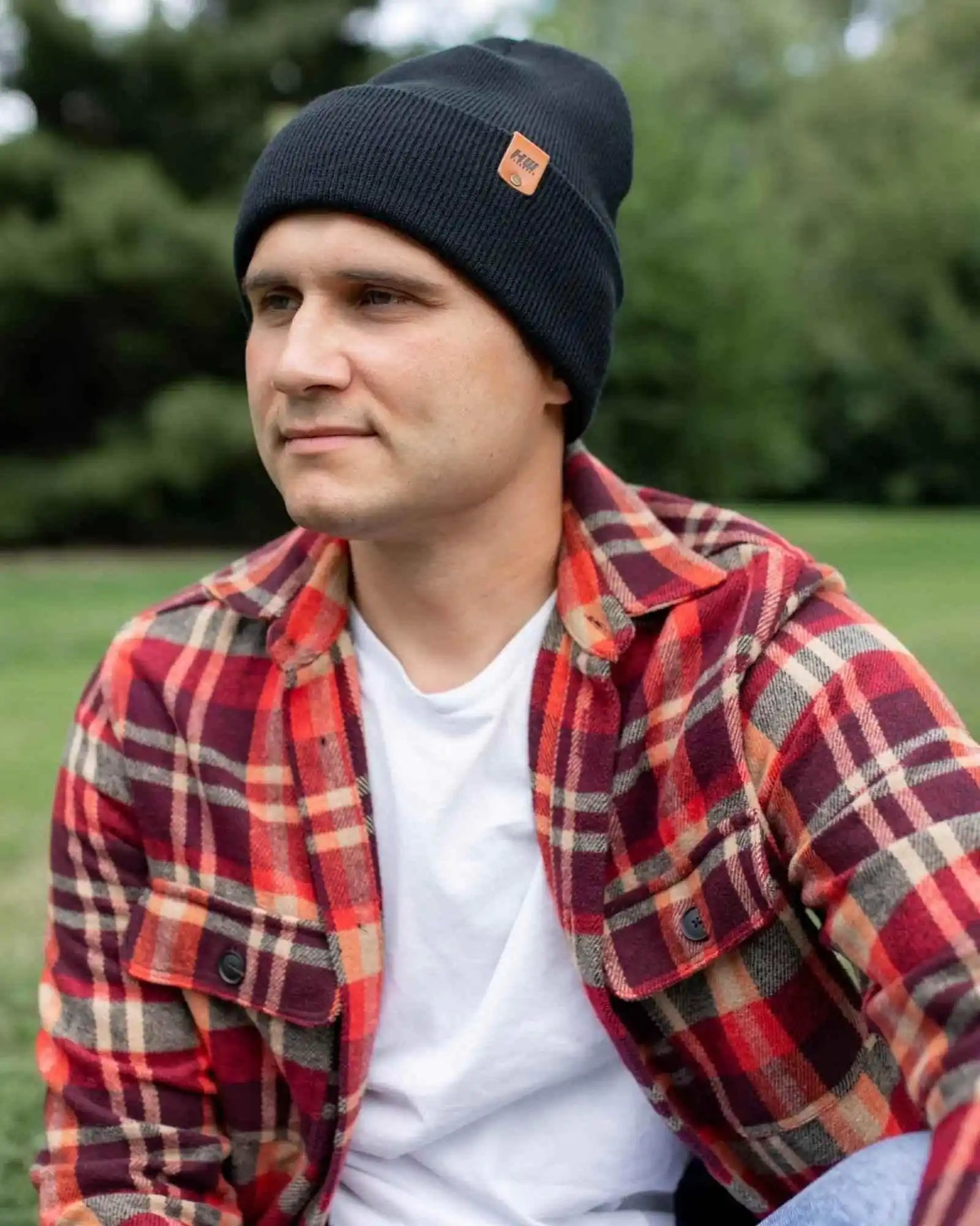 Charcoal black ribbed cuffed beanie with fold-over brim and small leather logo patch.