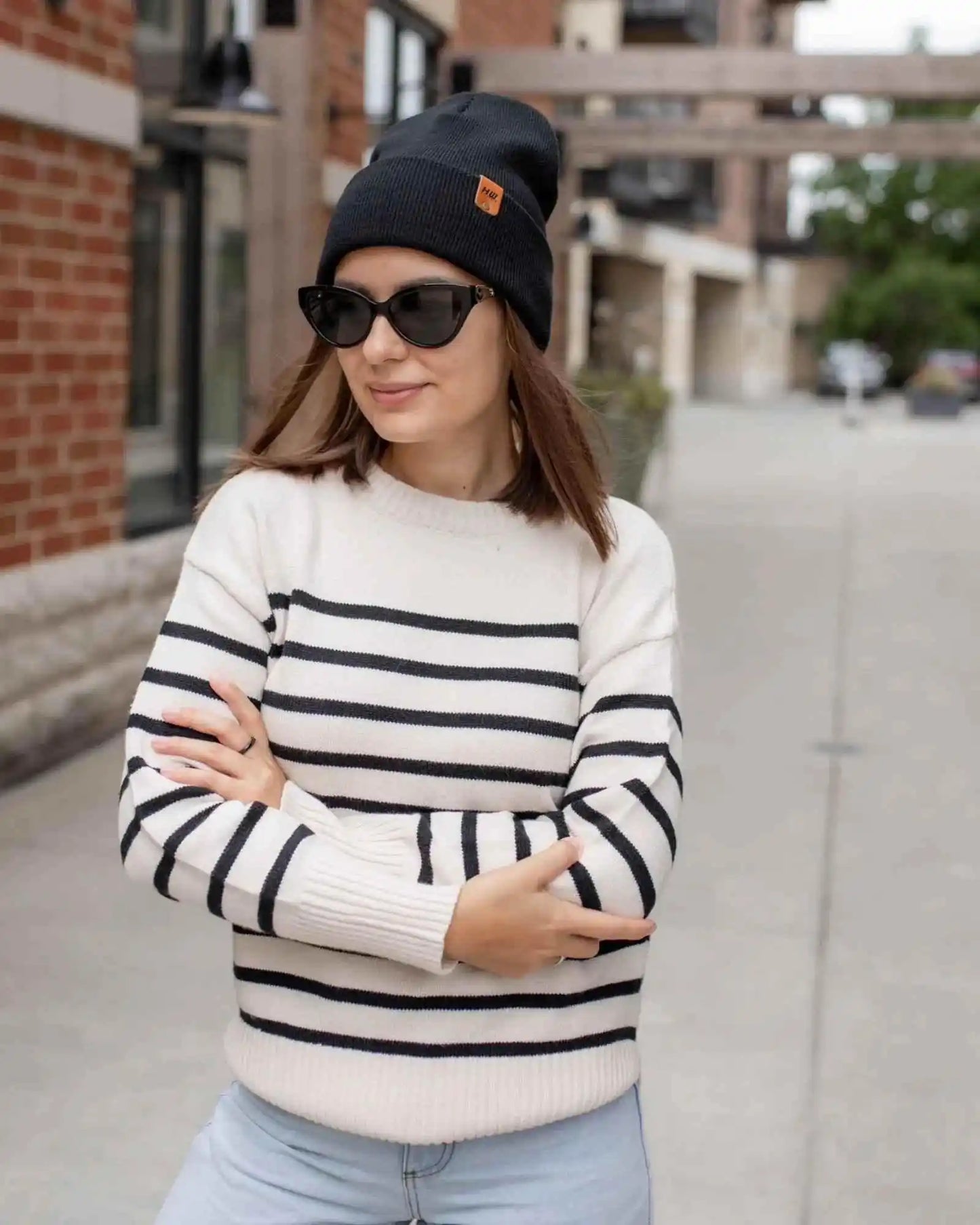Charcoal black cuffed knit beanie with striped logo patch and fold-over brim.