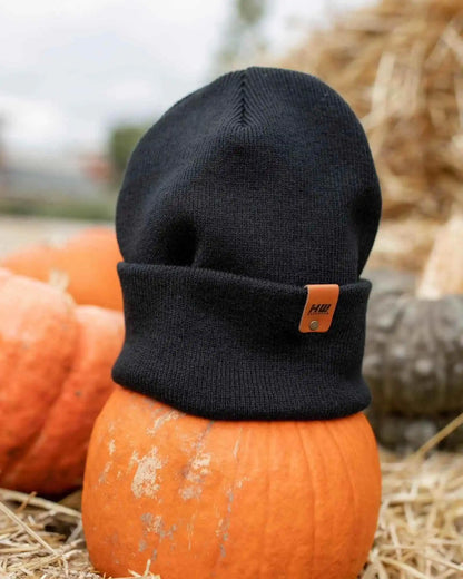 Charcoal black knit beanie with fold-over cuff and small rectangular logo patch.