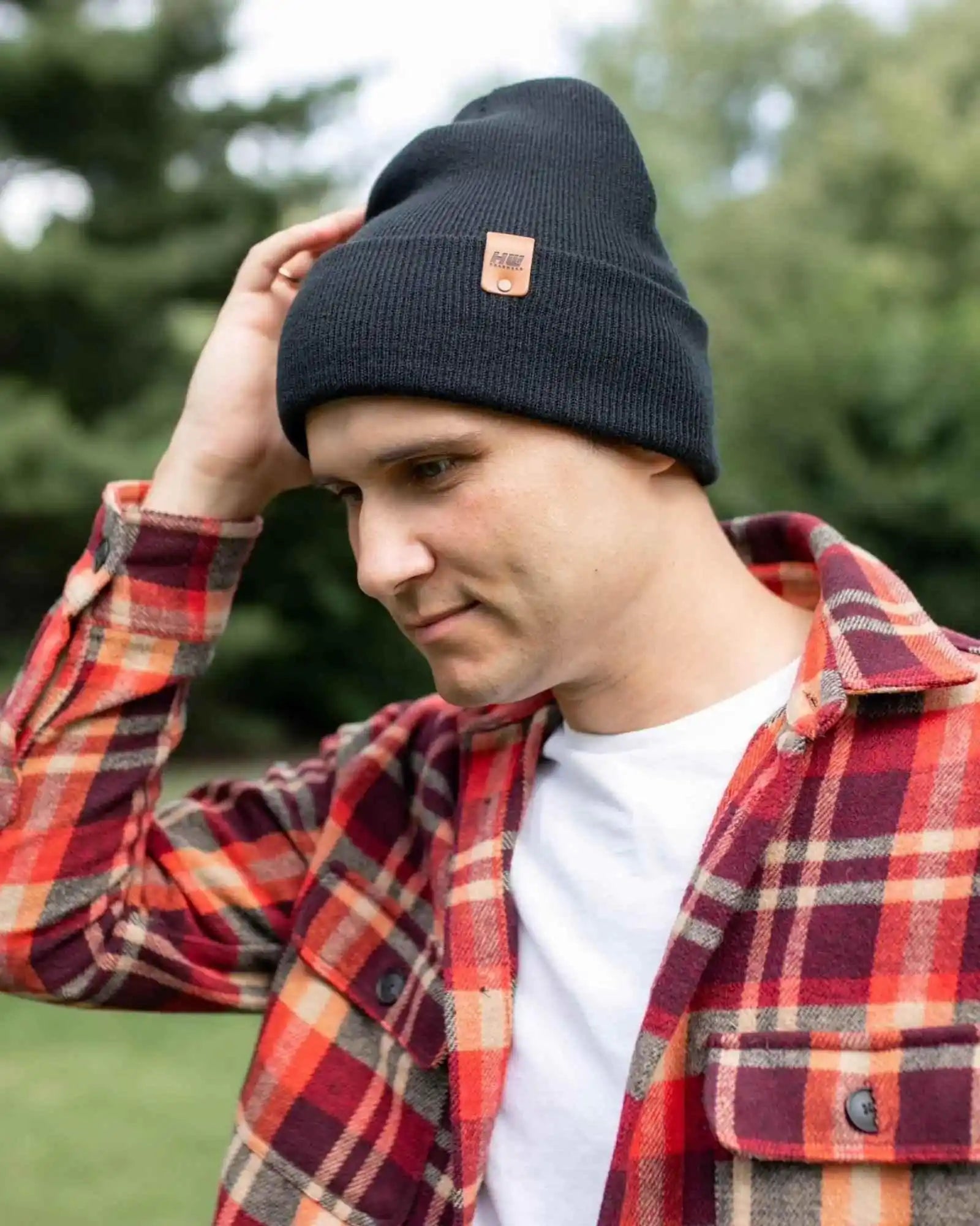 Charcoal black cuffed beanie with fold-over brim and small leather logo patch.