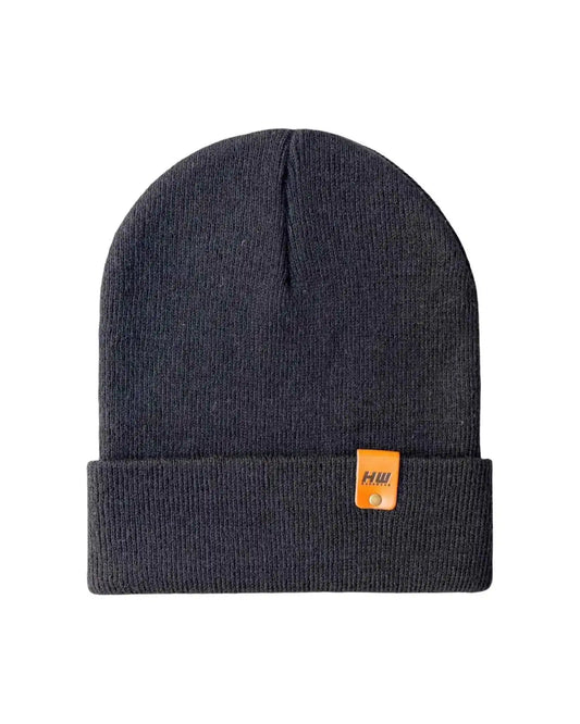Charcoal black cuffed beanie flat lay with small leather logo patch on cuff.