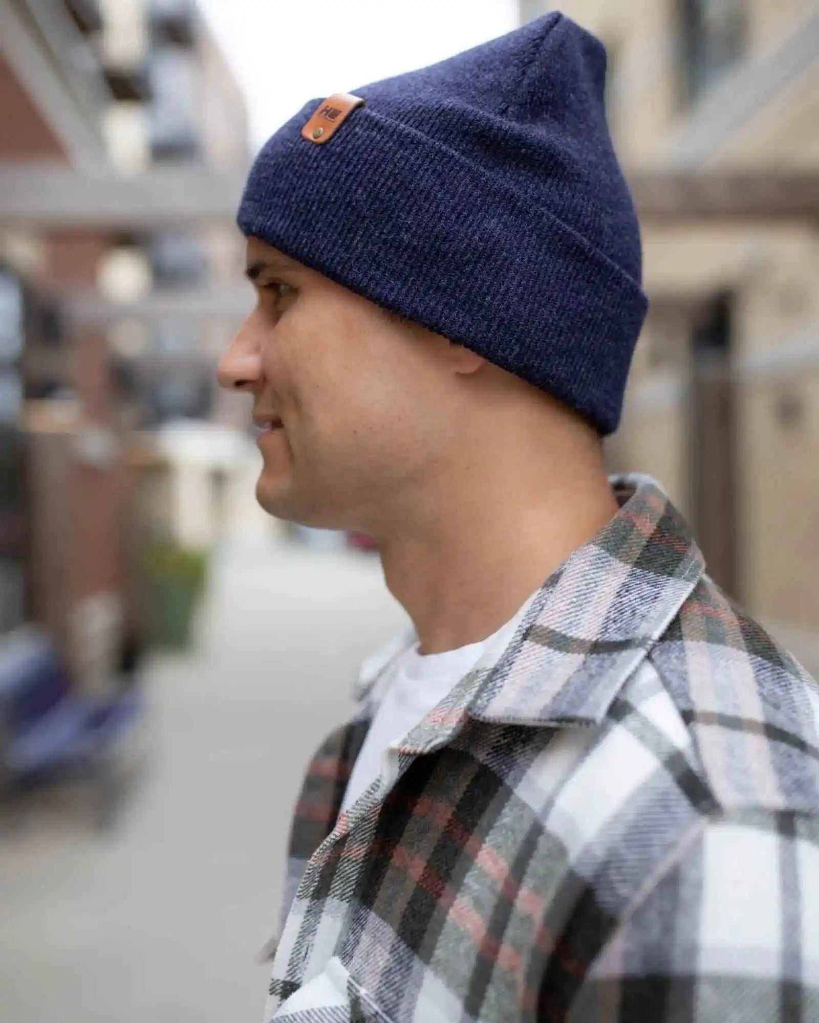 Denim blue knit beanie with tan logo patch and folded cuff